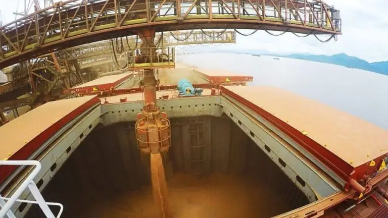 Imagem representa exportação do agro. Grãos sendo descarregados em um navio.